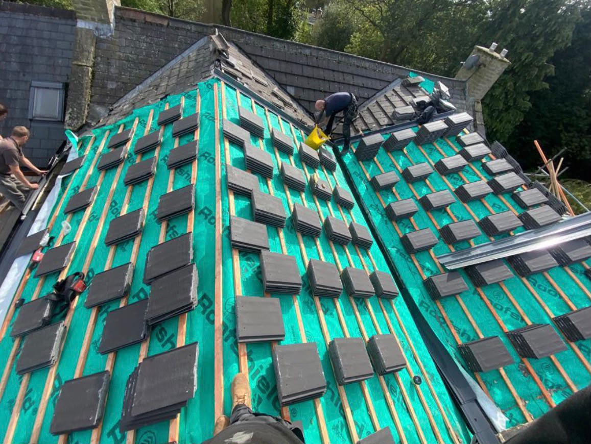 Natural slate tiles stacked on green breathable membrane ready for installation